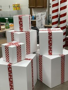 several white boxes with red and white bows on them are stacked up in a room