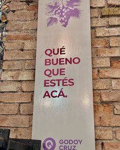 a sign hanging on the side of a brick building that says, que bueno que ests aca