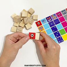 two hands are playing with wooden blocks and an owl themed sticker on the board