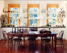 the dining room table is surrounded by chairs and windows with yellow panes on them