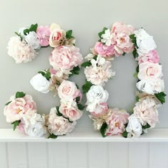 flowers arranged in the shape of the letter q on a white shelf against a gray wall