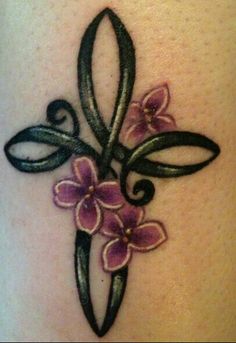 a cross with flowers on the side of her leg is shown in this tattoo design