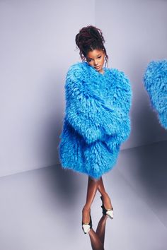 a woman in a blue fur coat posing for the camera