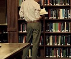 a man standing in front of a bookshelf with lots of books on it