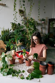 a woman sitting at a table surrounded by potted plants