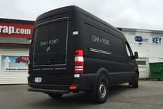 a black van parked in front of a building with writing on the back door and windows