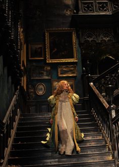 a woman is walking down the stairs in an old house