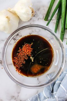 the ingredients for green beans and garlic are in a glass bowl on a marble countertop