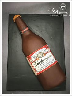 a cake shaped like a bottle of budweiser on top of a black plate