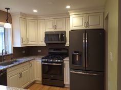 a kitchen with white cabinets and stainless steel appliances in the center, along with granite counter tops