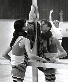 two women standing next to each other on top of a pole