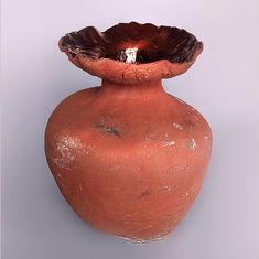 a large red vase with a small bowl in the middle on a gray background,