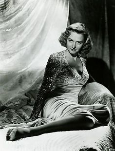 a black and white photo of a woman sitting on a bed