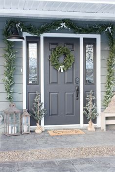 a gray front door with wreaths and lanterns on the side walk next to it