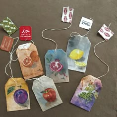 several tags with fruit on them are hanging from twine strings, and there is no string attached to the tags