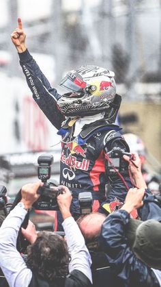 a man in a racing suit is surrounded by photographers