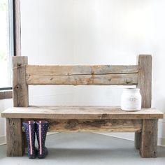 a wooden bench sitting in front of a window next to a pair of rubber boots