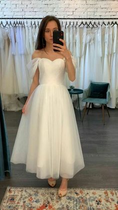 a woman in a white dress taking a selfie