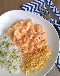 a white plate topped with rice and meat covered in gravy next to a fork