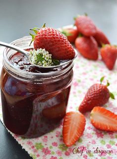 a jar filled with jam and strawberries on top of a table