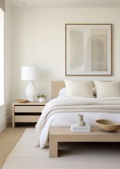 a bed with white sheets and pillows in a bedroom next to a painting on the wall