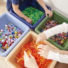 three children playing with beads in plastic bins