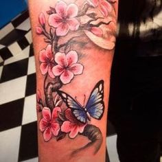 a woman's arm with pink flowers and a butterfly on the left side of her arm