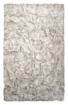 a white rug with shaggy fur on the top and bottom part, in an angled position