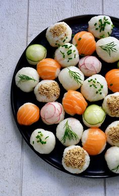 a black plate filled with assorted sushi on top of a white tablecloth