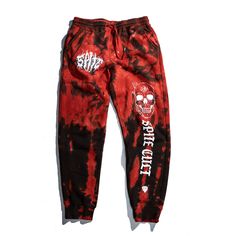 a red and black tie dye sweat pants with white skulls on the side, in front of