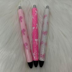 three pink and silver pens sitting on top of a white fur covered floor next to each other