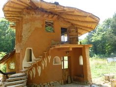 an adobe - style building with steps leading up to the upper floor and second story