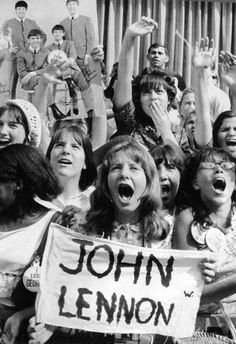 a group of young people holding up signs and shouting in front of a wall with the words john lemon on it