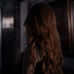 a woman with long red hair standing in a dark room