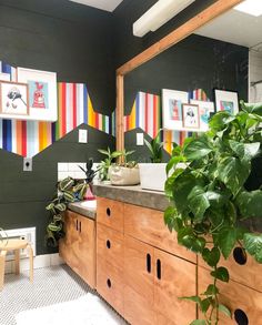 a bathroom with green plants and pictures on the wall above the sink, along with potted plants