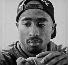 a black and white photo of a young man with a hat on holding something in his hands