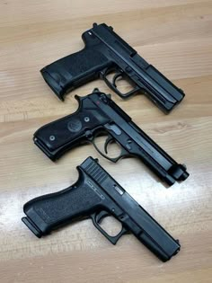 two handguns sitting on top of a wooden table