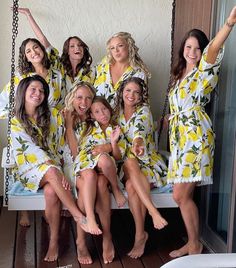 a group of women in yellow and white robes sitting on a porch swing with their arms up