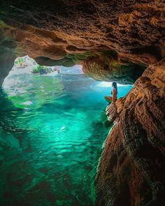 a person sitting on a surfboard in the middle of a cave filled with water