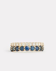 a gold ring with blue sapphires and white diamonds on the sides, set in 18k yellow gold