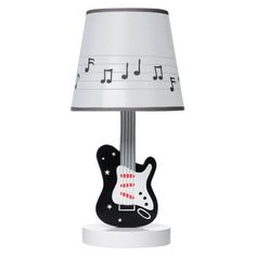 a lamp with a black and white guitar on it's base next to a light shade