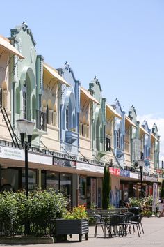 a row of buildings with tables and chairs on the sidewalk