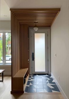 an entry way with a bench and wooden paneling on the wall, next to a large window