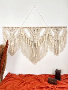 a wall hanging made out of macrame and tassels on a bed