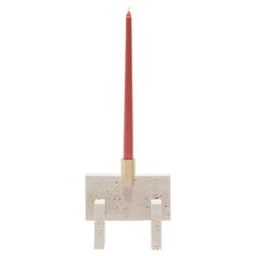 a red candle sitting on top of a white block