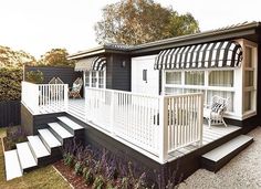 a white porch with steps leading up to it and a black and white awning