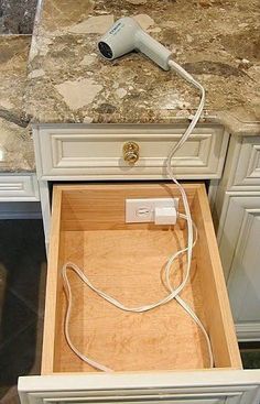 an open drawer with a hair dryer plugged into the top and cord connected to it