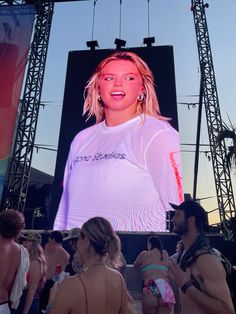 a group of people standing in front of a large screen with a woman on it