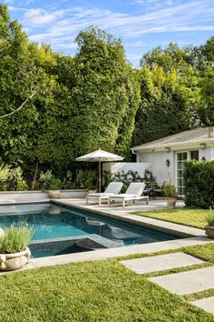 a backyard with a swimming pool and lawn furniture in the foreground, surrounded by trees