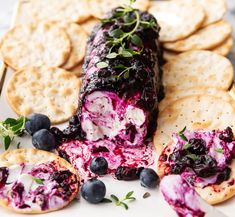 a plate with crackers and blueberries on it next to an appetizer